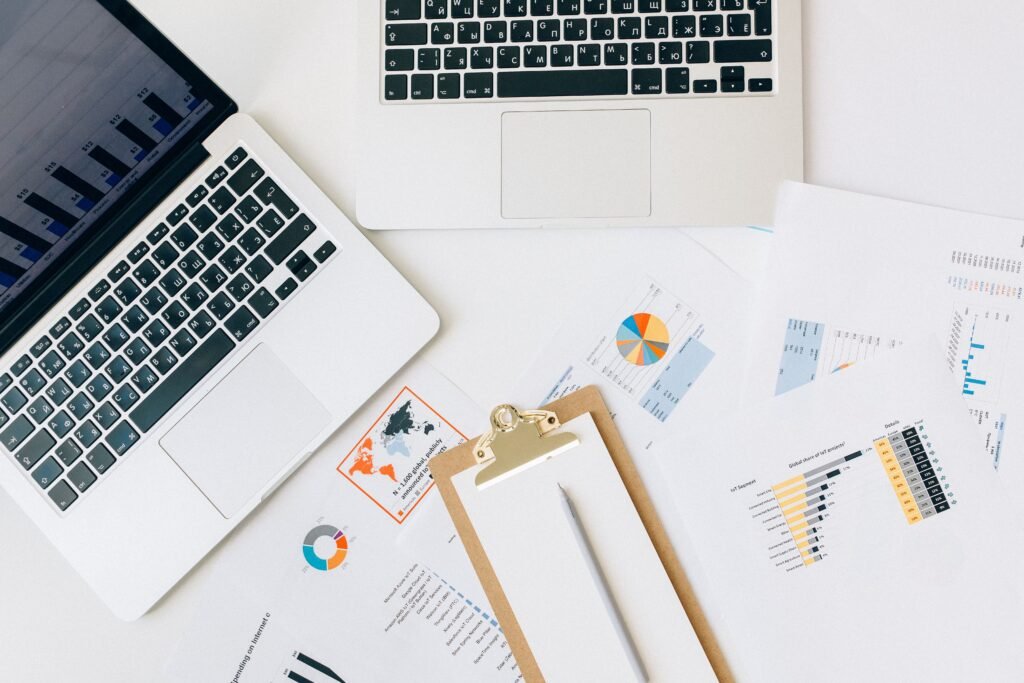 Printed analytics reports with charts beside two laptops